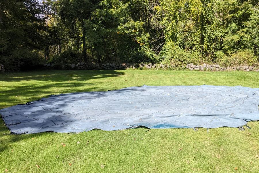 Laying a pool cover on grass to check for holes